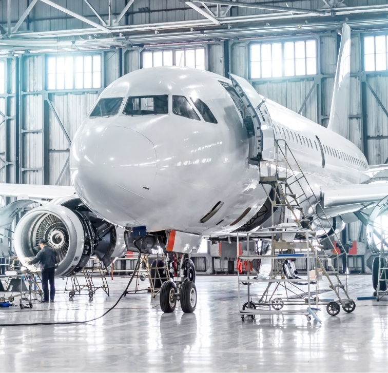 Aircraft maintenance in a spacious hangar with technicians working on a commercial jet.